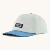 Patagonia p6 label trad cap in white with a blue visor. Shows air holes on the top and brand patch on the front