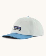 Patagonia p6 label trad cap in white with a blue visor. Shows air holes on the top and brand patch on the front