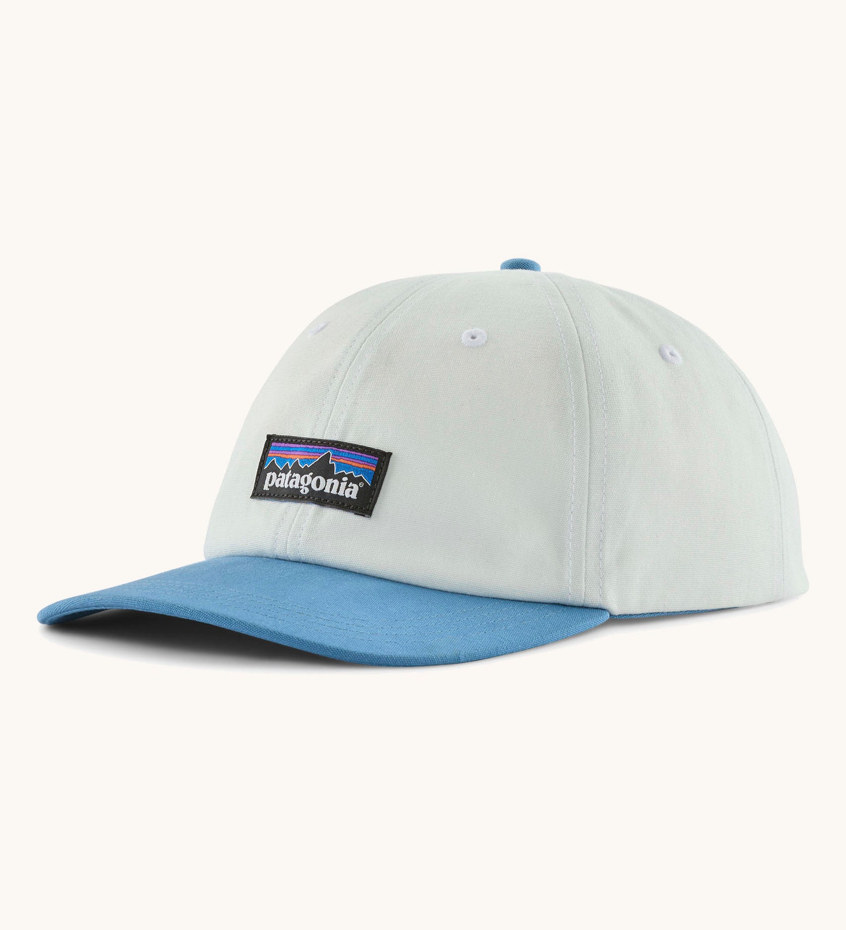 Patagonia p6 label trad cap in white with a blue visor. Shows air holes on the top and brand patch on the front