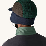 Back of man wearing Patagonia Adult Range Earflap Cap in denim, and cascade fleece with denim flap down and tied at the chin, for sale at Babipur.
