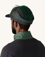 Back of man wearing Patagonia Adult Range Earflap Cap in denim, green fleece and a green/grey check lining, buy now at Babipur.