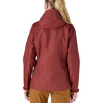 The back of the Patagonia Women's Torrentshell 3L Rain Jacket - Oxide Red. The image shows a person wearing the jacket to show the fit of the coat from the back and the hood