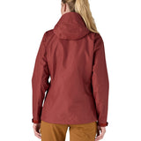 The back of the Patagonia Women's Torrentshell 3L Rain Jacket - Oxide Red. The image shows a person wearing the jacket to show the fit of the coat from the back and the hood