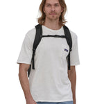 A person wearing the Patagonia Refugio Day Pack 30L Black, showing the sholder straps and the chest strap closed