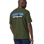 Organic Cotton Patagonia t-shirt in dark green, being worn by an adult. On the back is a large Patagonia mountain range logo