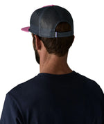 Man wearing wearing Patagonia's airfarer cap in pink with blue mesh back panel shows adjustable strap on the back