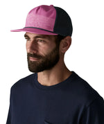 Man wearing Patagonia's airfarer cap in pink with blue mesh back panel.  Hat has a trucker style and wide brim