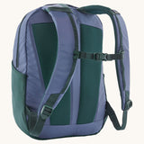 A reverse image of the Patagonia 24L current blue atom day pack in  showing the padded shoulder strap and dark green chest strap detail