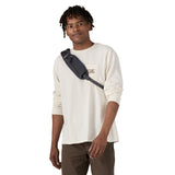A man wearing the Patagonia atom sling 8L bag in smolder blue available at Babipur.