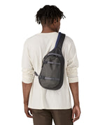 The back of a man wearing the Patagonia atom sling 8L bag in smolder blue available at Babipur.