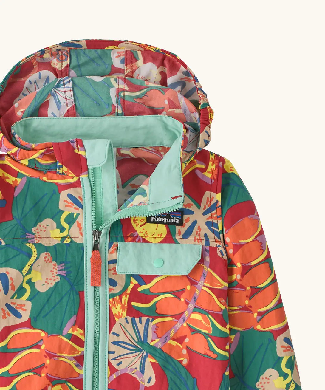 Close up of Patagonia red baby baggies hooded jacket with repeating abstract tropical pattern. Shows light blue chest pocket with popper
