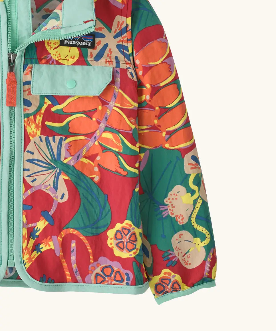 Close up of Patagonia red baby baggies hooded jacket with repeating abstract tropical pattern. Shows light blue hem and cuff trim