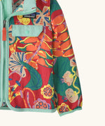 Close up of Patagonia red baby baggies hooded jacket with repeating abstract tropical pattern. Shows light blue hem and cuff trim