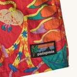 Close up of Patagonia baby baggies quick drying shorts in red with repeating abstract floral design. Shows brand patch on the hem