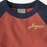 A close up of the Patagonia Baby Crew Sweatshirt in wiggle fitz / potters red showing the navy collar and brand name stitch detail