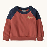 Patagonia Baby Crew Sweatshirt in wiggle fitz / potters red available at Babipur. A red and navy colourblock sweater with the brand name in a handwritten style stitched on the chest