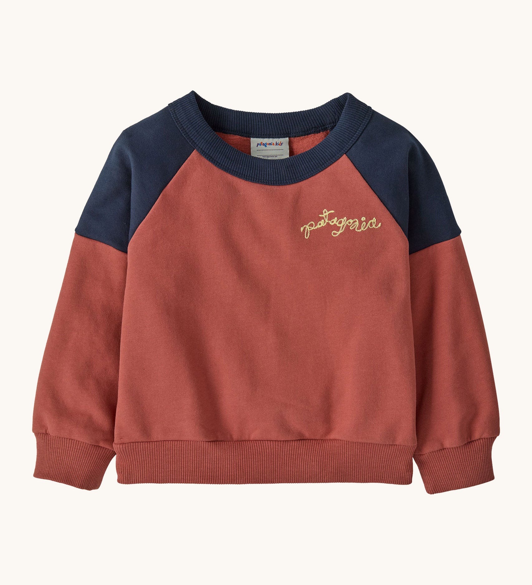 Patagonia Baby Crew Sweatshirt in wiggle fitz / potters red available at Babipur. A red and navy colourblock sweater with the brand name in a handwritten style stitched on the chest