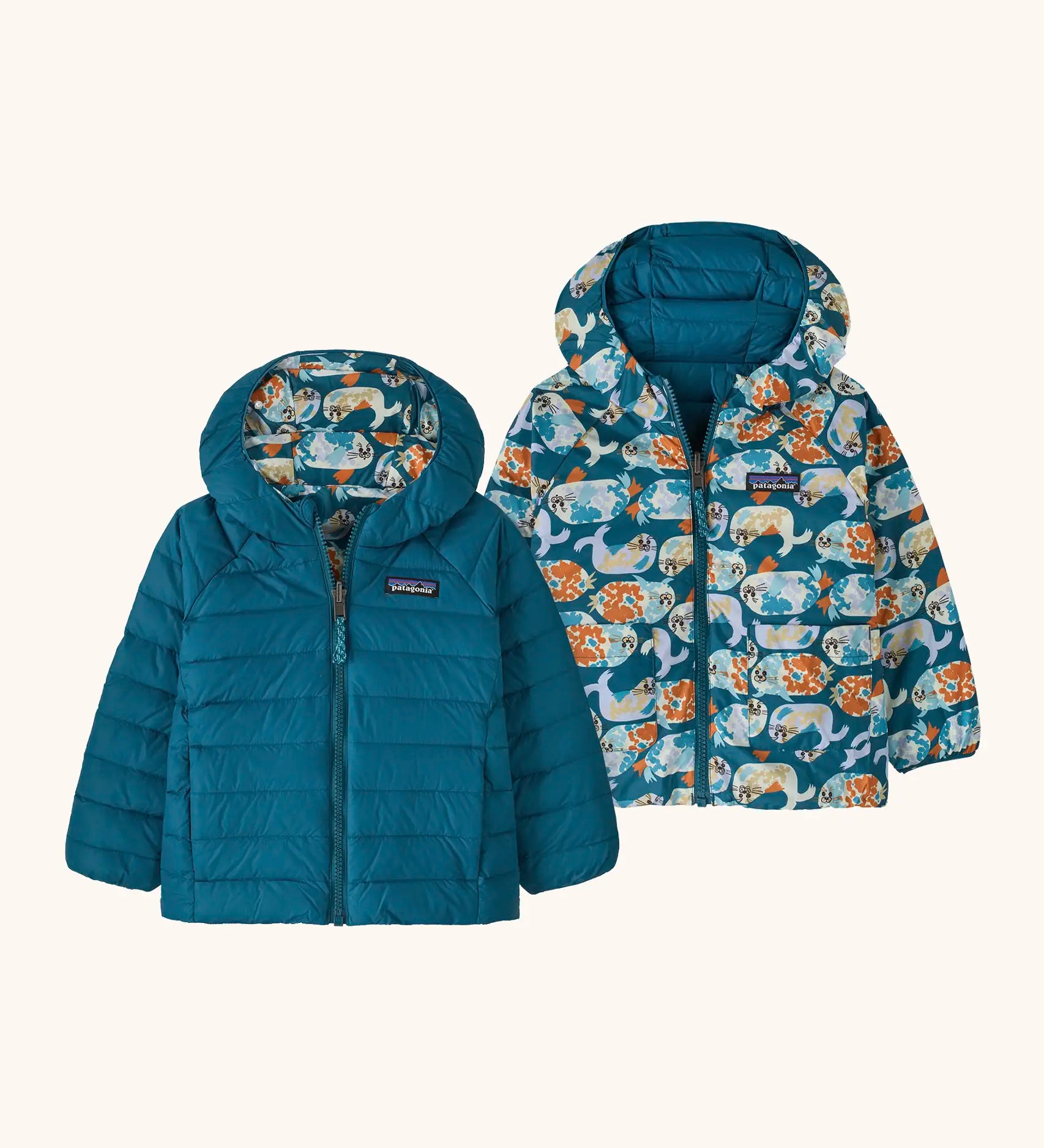 Patagonia baby reversible down hooded sweater jacket in glacial blue with a repeating playful seal design on the reverse. Features a full front zip and pockets