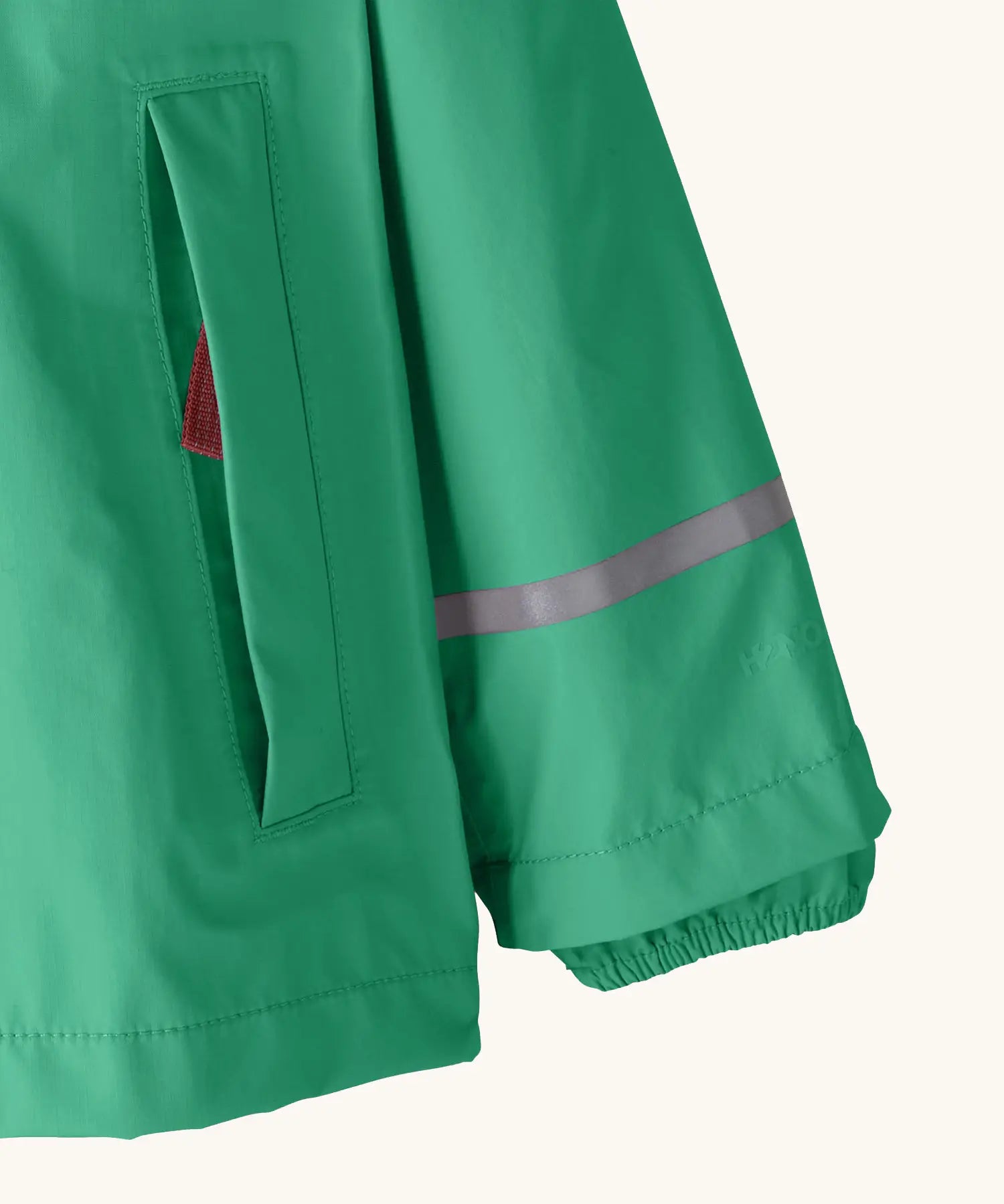 Patagonia little kids torrentshell 3 layer rain jacket in green showing side pocket and reflective strip around arm