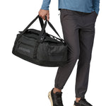 A person carrying the Patagonia Black Hole Duffel 40L using the carry handles