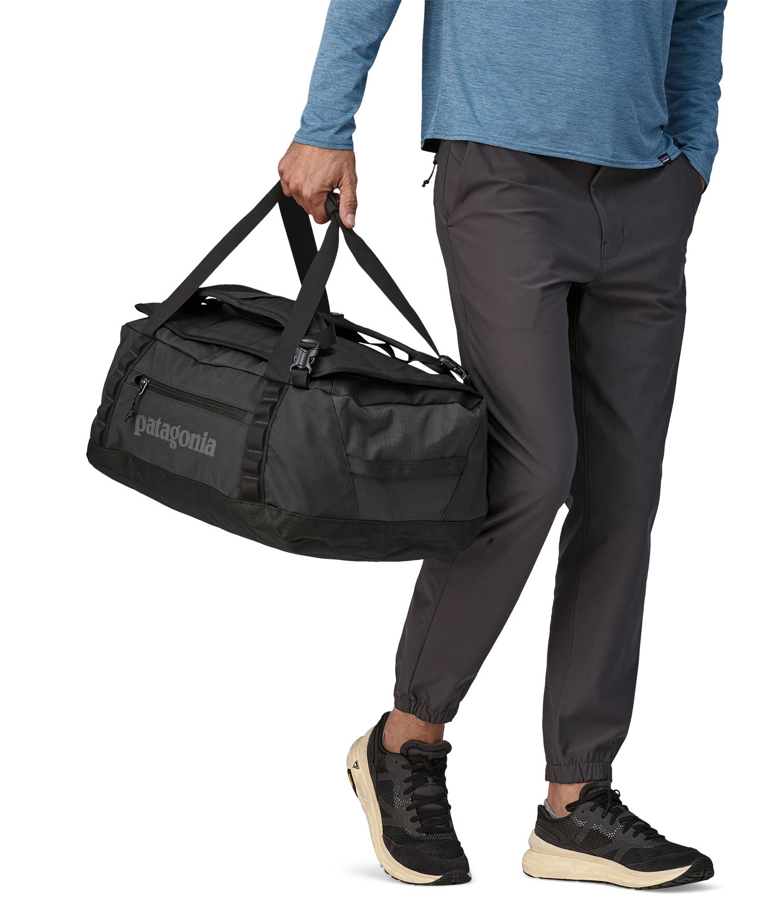 A person carrying the Patagonia Black Hole Duffel 40L using the carry handles