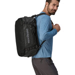 A person carrying the Patagonia Black Hole Duffel 40L on their shoulder using the shoulder straps