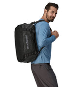 A person carrying the Patagonia Black Hole Duffel 40L on their shoulder using the shoulder straps