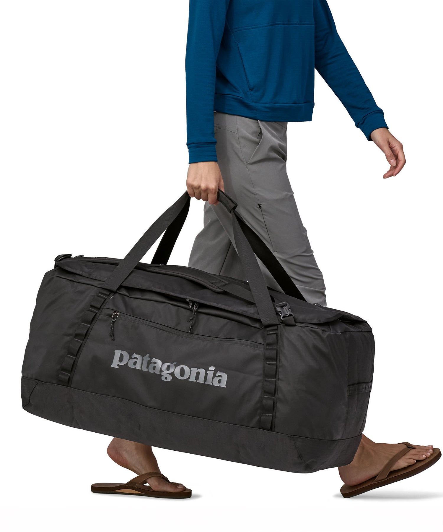 A person carrying the Patagonia Black Hole Duffel 100L Black with the carry handles
