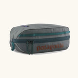 Patagonia black hole cube 3 litre bag in grey with green zip detail and brown brand text on top panel