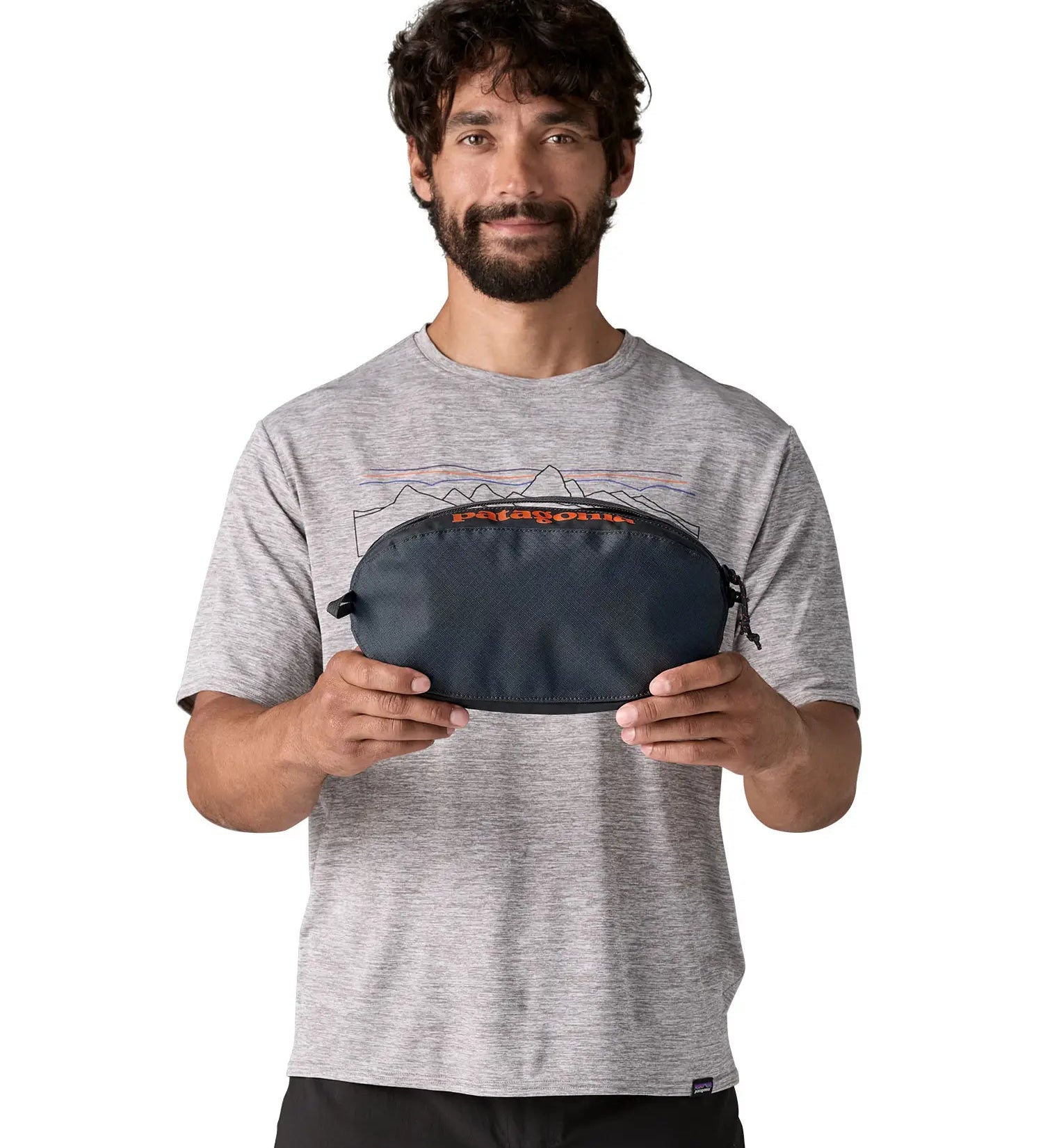 Man holding Patagonia black hole cube 3 litre bag in dark blue