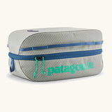 Patagonia black hole 6 litre cube bag in light gret with blue zip detail and turquoise brand text on front panel