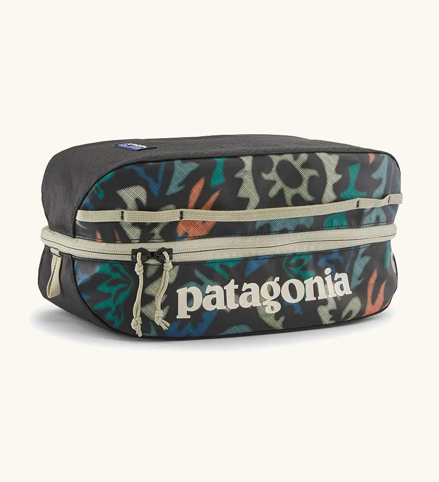 Patagonia black hole 6 litre cube bag in black with abstract pattern design on front panel and cream zip detail
