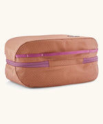 Underside of Patagonia black hole 6 litre cube bag in orange showing purple zip running underneath