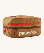 Patagonia black hole 6 litre cube bag in talon gold available at Babipur. A 100% recycled material cube bag in dark yellow with dark red detail. Features 1 main zip compartment with a light blue brand text on the top and a brand patch stitched on the side