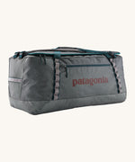 Patagonia black hole 100L duffel bag in noble grey available at Babipur. A dark grey bag with green trim and brown branding on the side. Features shoulders straps and a handle on the top for easy carrying.