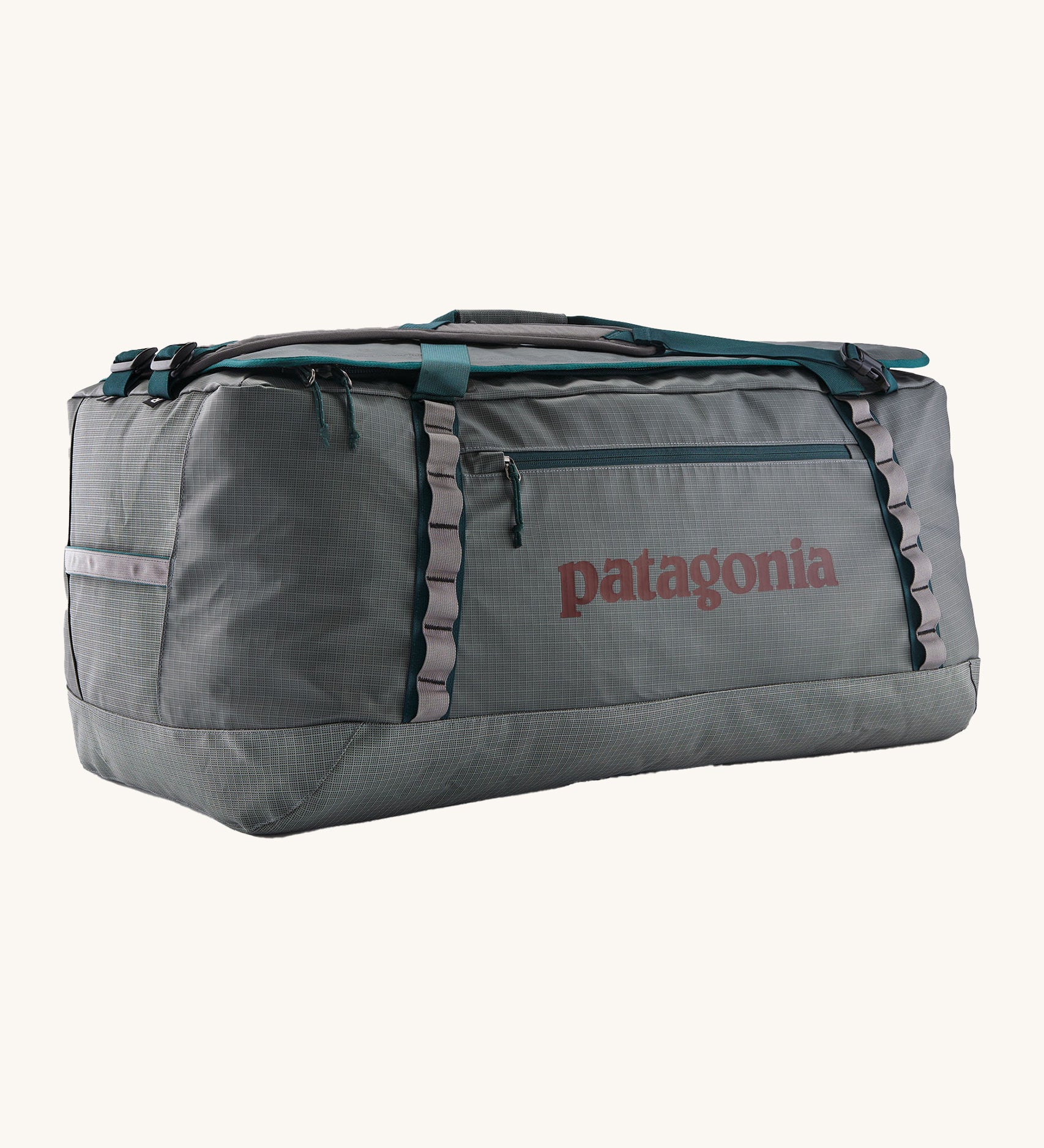 Patagonia black hole 100L duffel bag in noble grey available at Babipur. A dark grey bag with green trim and brown branding on the side. Features shoulders straps and a handle on the top for easy carrying.