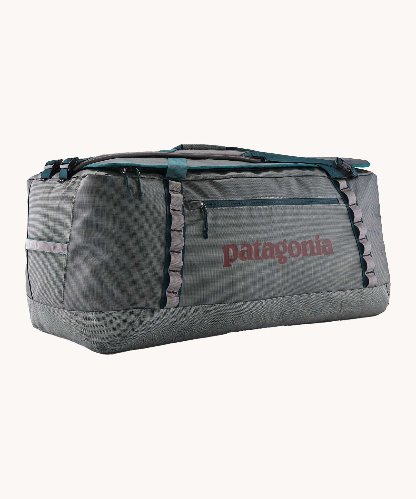 Patagonia black hole 100L duffel bag in noble grey available at Babipur. A dark grey bag with green trim and brown branding on the side. Features shoulders straps and a handle on the top for easy carrying.
