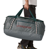 A man carrying the Patagonia black hole 100L duffel bag in noble grey available at Babipur. 
