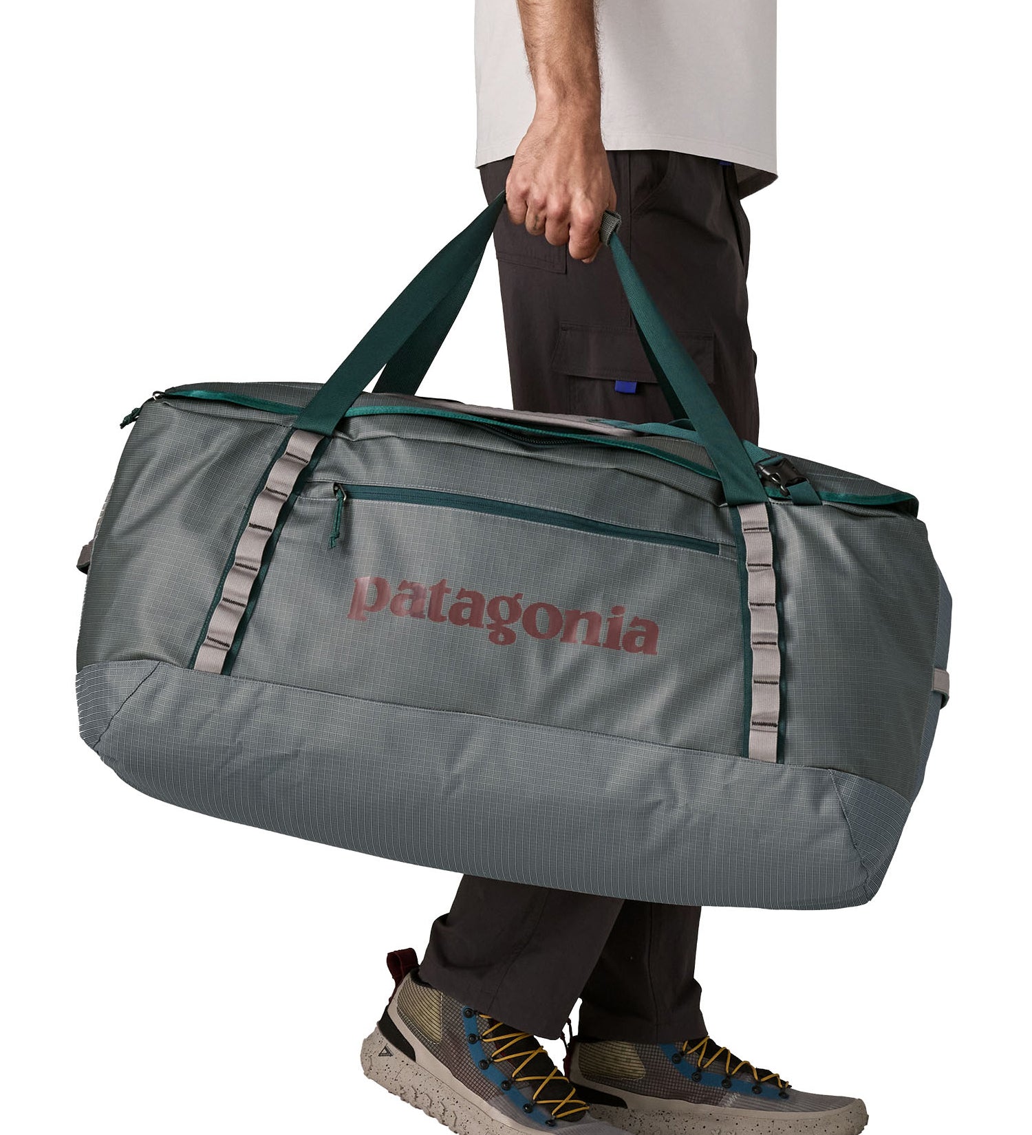 A man carrying the Patagonia black hole 100L duffel bag in noble grey available at Babipur. 