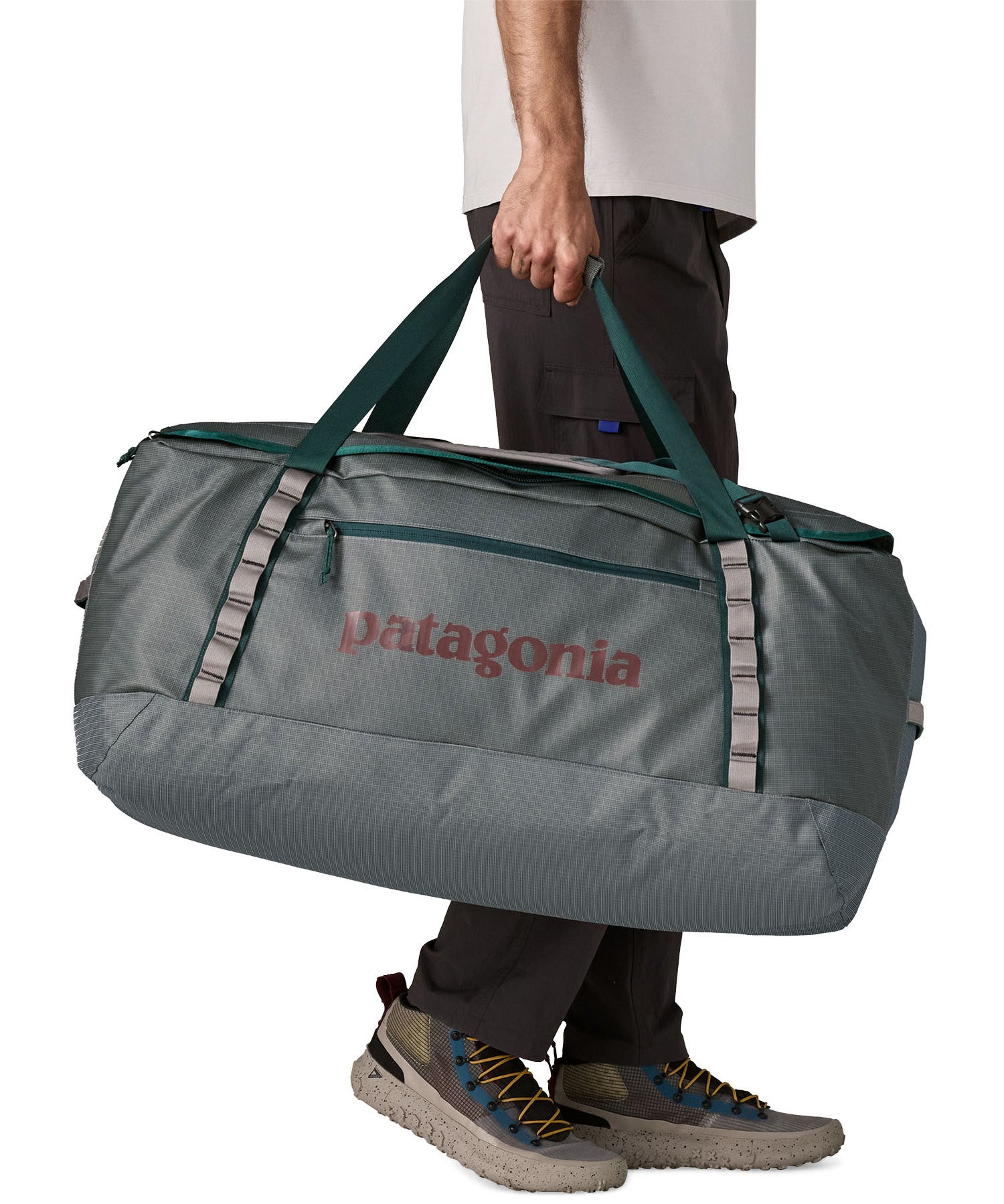 A man carrying the Patagonia black hole 100L duffel bag in noble grey available at Babipur. 