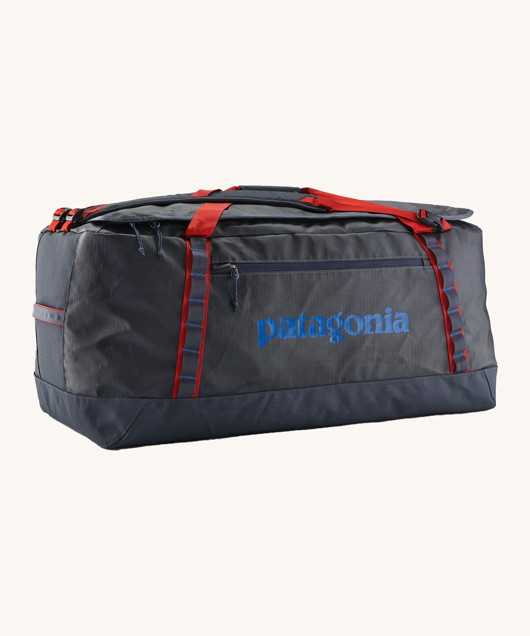 Patagonia black hole 100L duffel bag in smolder blue / amanita red available at Babipur. A dark blue bag with red trim and blue branding on the side. Features shoulders straps and a handle on the top for easy carrying.