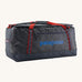 Patagonia black hole 100L duffel bag in smolder blue / amanita red available at Babipur. A dark blue bag with red trim and blue branding on the side. Features shoulders straps and a handle on the top for easy carrying.