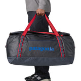 A man carrying the Patagonia black hole 100L duffel bag in smolder blue / amanita red available at Babipur. 