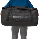 A person holding the Patagonia Black Hole Duffel 100L Black in their hands to show the size
