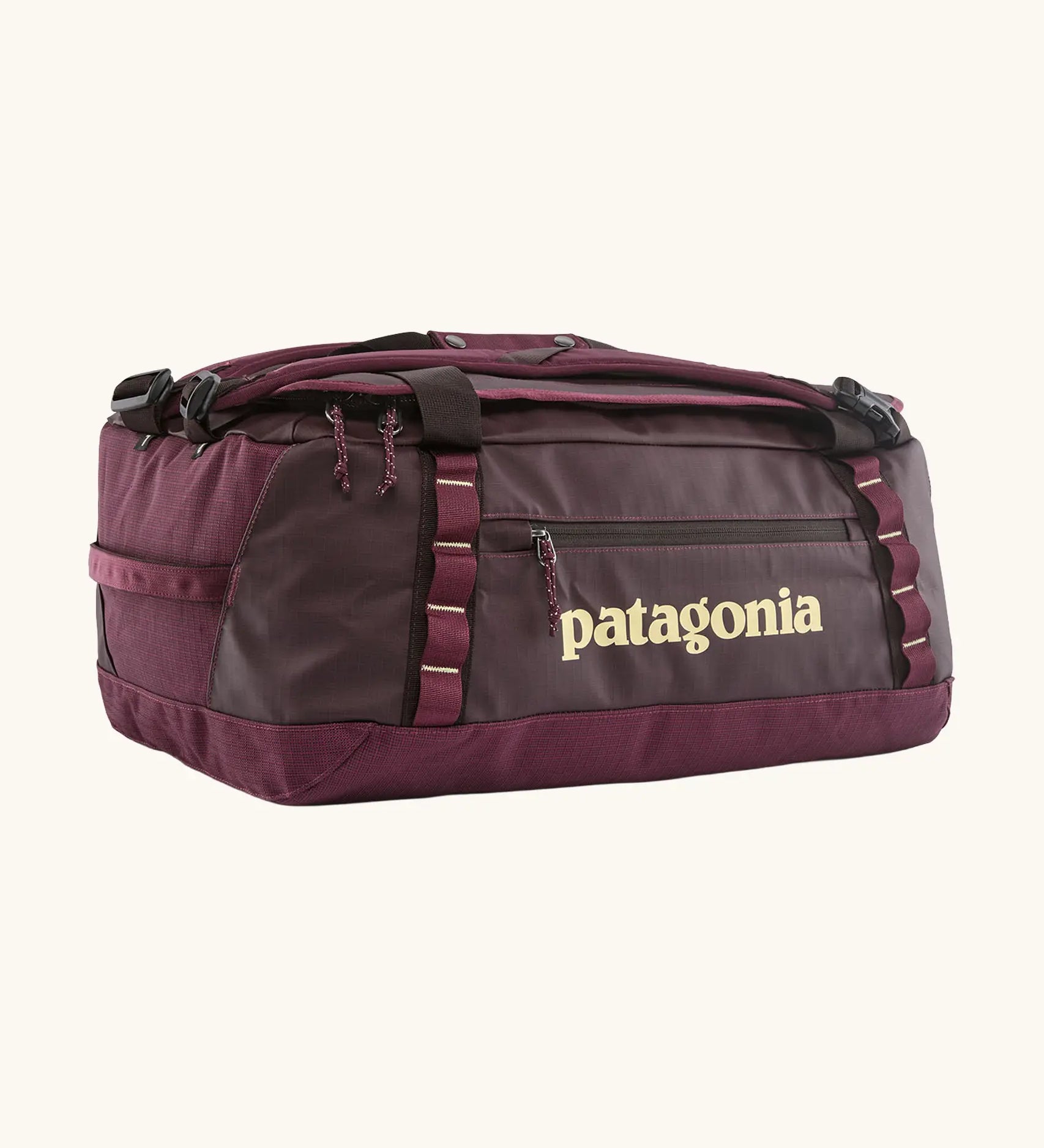 Patagonia black hole 70L duffel bag in Berry Fig. A deep maroon bag with yellow trim and Patagonia branding on the side. Features shoulders straps and a handle on the top for easy carrying.