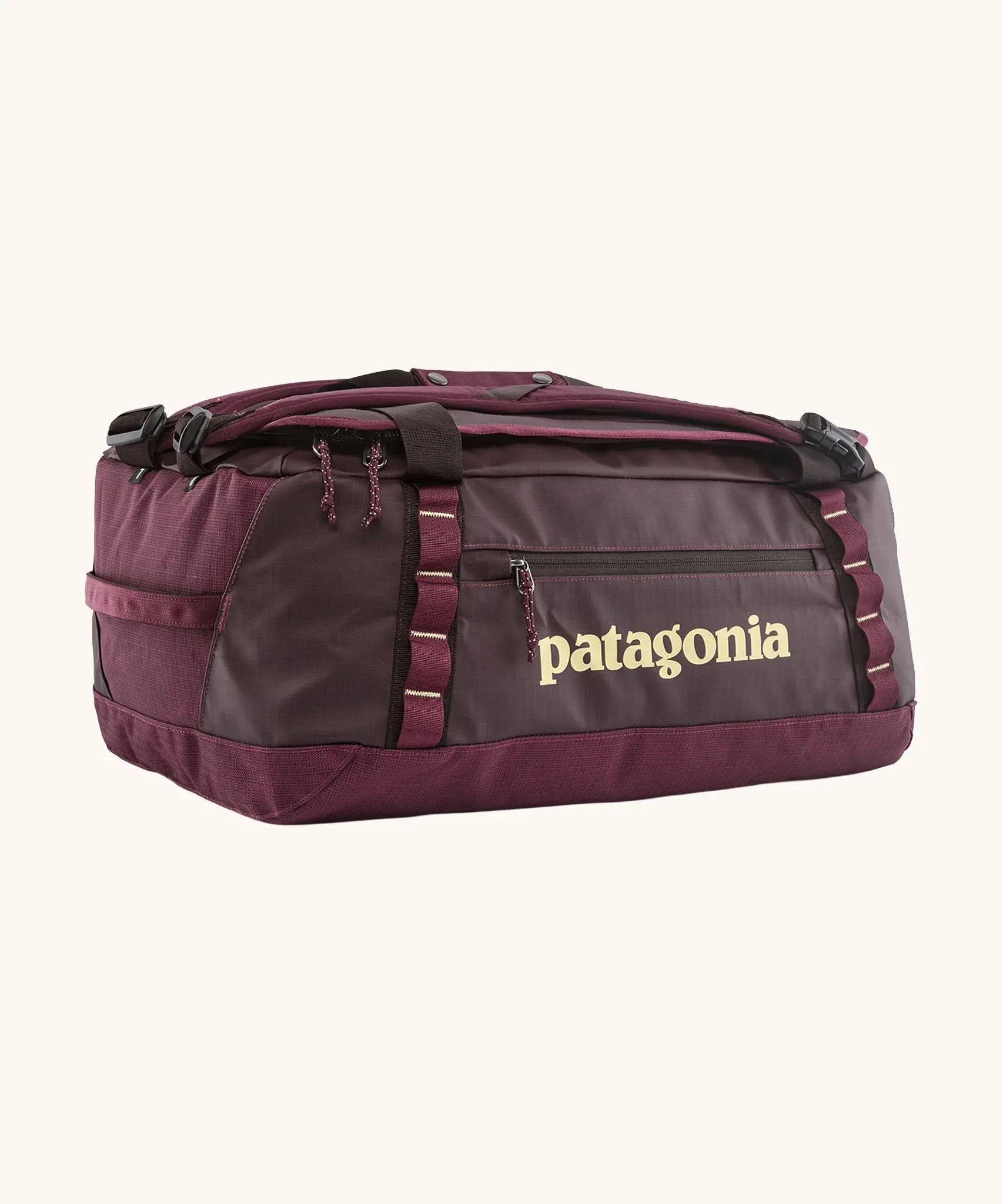 Patagonia black hole 70L duffel bag in Berry Fig. A deep maroon bag with yellow trim and Patagonia branding on the side. Features shoulders straps and a handle on the top for easy carrying.
