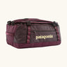 Patagonia black hole 70L duffel bag in Berry Fig. A deep maroon bag with yellow trim and Patagonia branding on the side. Features shoulders straps and a handle on the top for easy carrying.