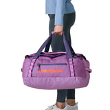 A woman carrying the Patagonia black hole 40l duffel bag in brisk purple available at Babipur. 