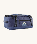 Patagonia black hole 40l duffel bag in current blue available at Babipur. A blue bag with black trim and a mountain graphic on the side. Features shoulders straps and a handle on the top for easy carrying.