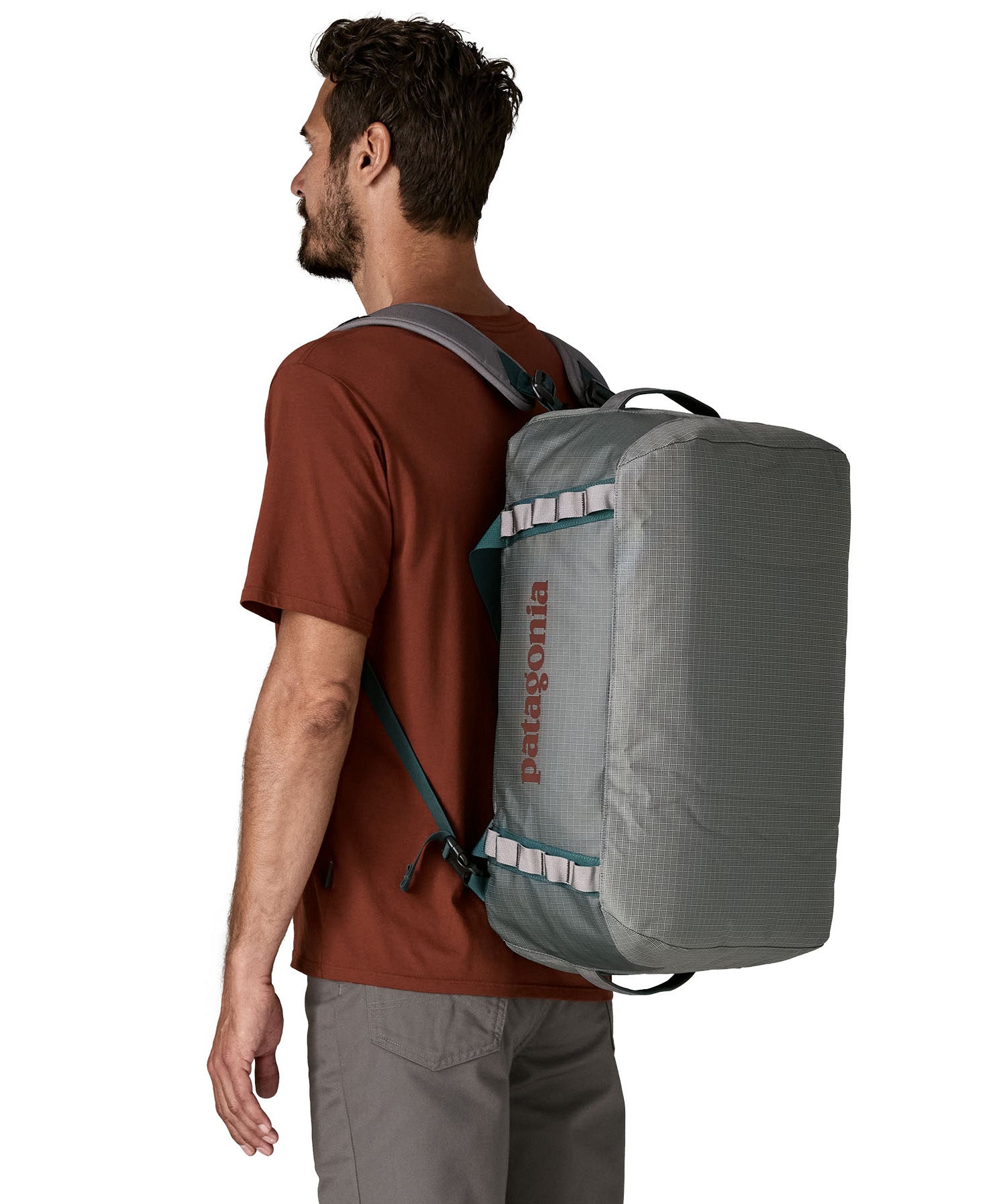 A man carrying the Patagonia black hole 40l duffel bag in noble grey on his back by the shoulder straps. Backpack available at Babipur. 